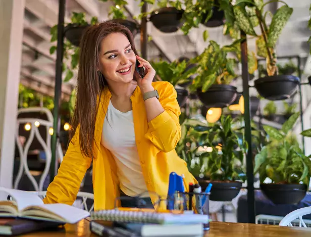 smiling-woman-speaking-by-mobile-phone-her-office